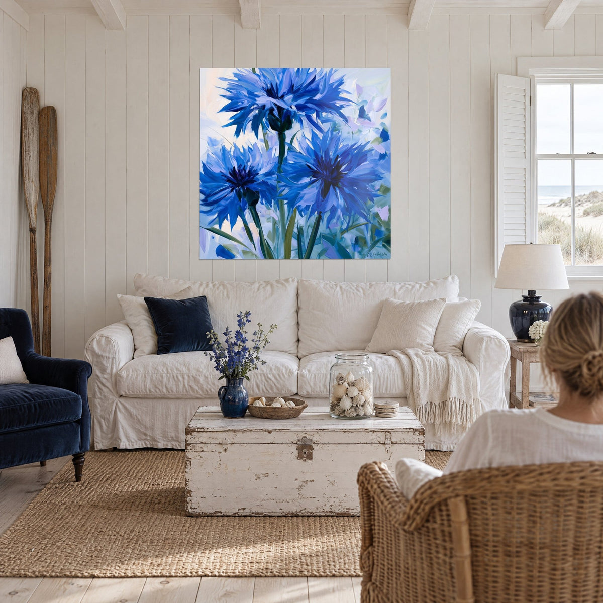 Tableau bleuets en fleurs, pétales bleu cobalt et lavande, tiges vert émeraude, au-dessus d'un canapé dans un salon lumineux