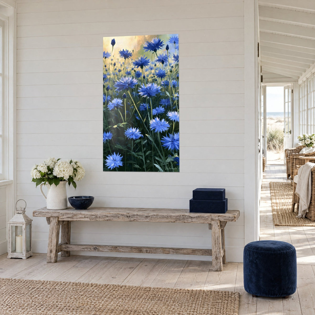 Tableau fleurs de centaurées bleu outremer, tiges vert olive en contre-jour ambré, vue de trois-quarts, console en bois, maison de bord de mer