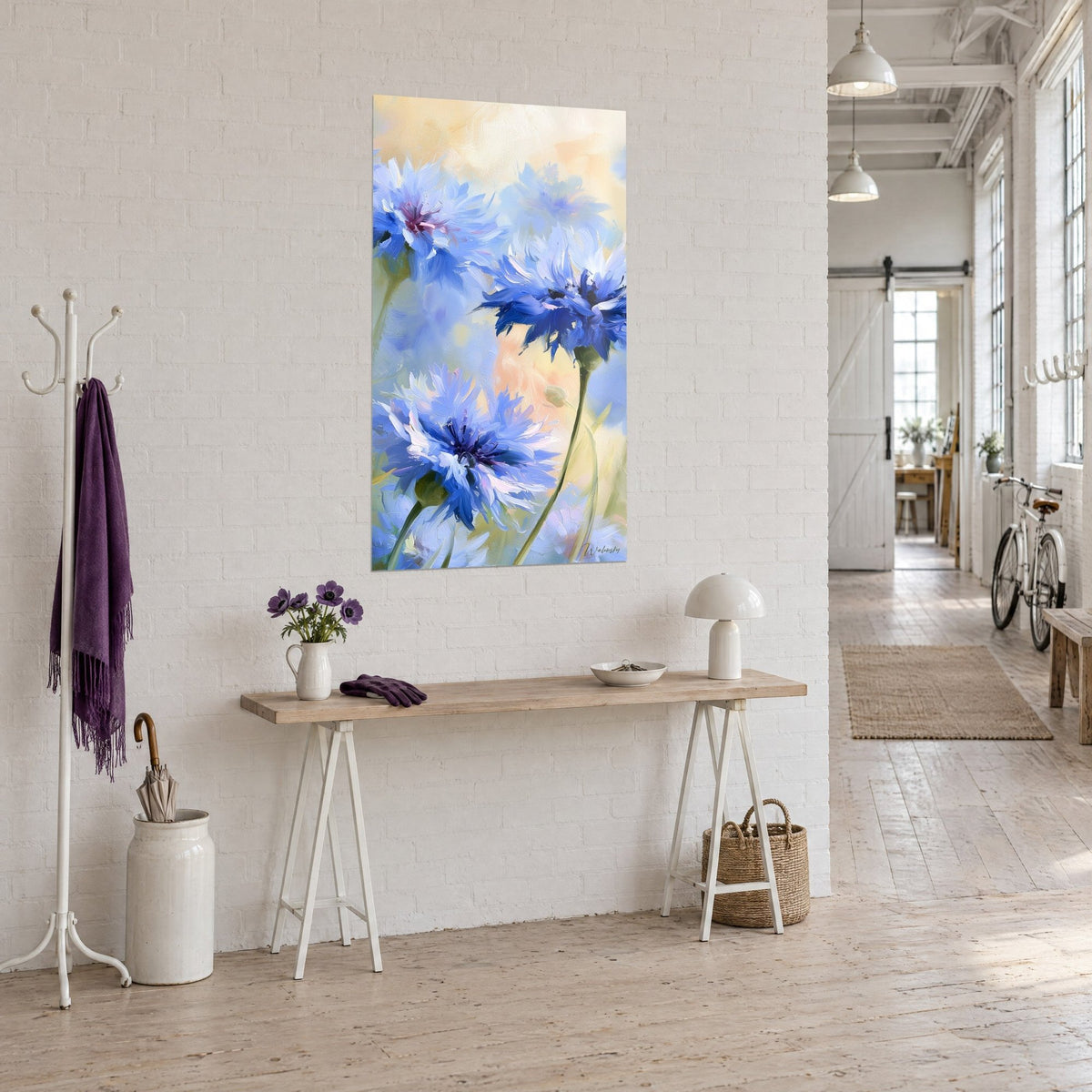 Wall art of indigo and lavender cornflowers with olive green stems, on a white wall at the end of a wooden console, loft