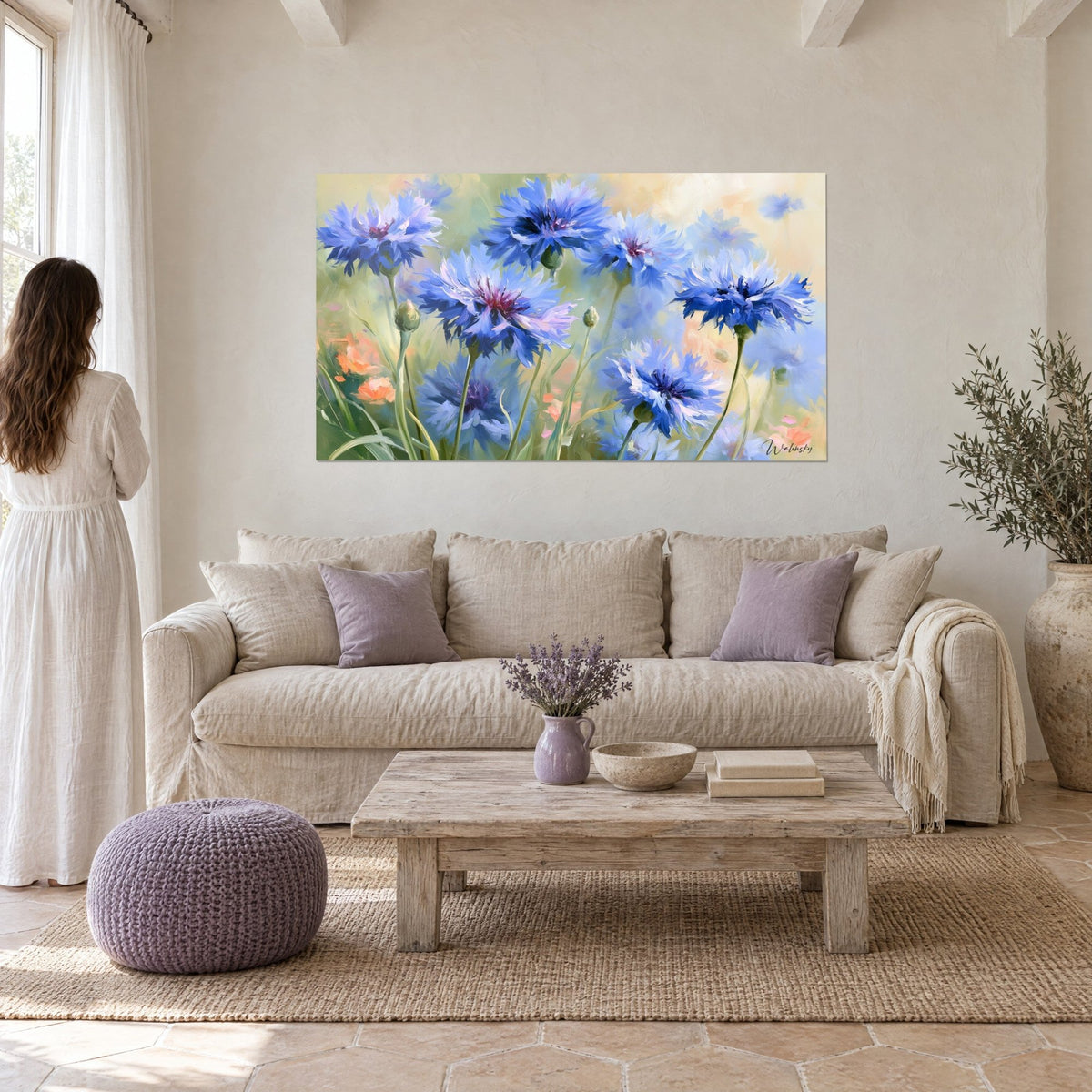Tableau bouquet de bleuets bleu outremer aux cœurs pourpres sur fond vert tendre, femme de dos, au-dessus d'un canapé dans un salon lumineux