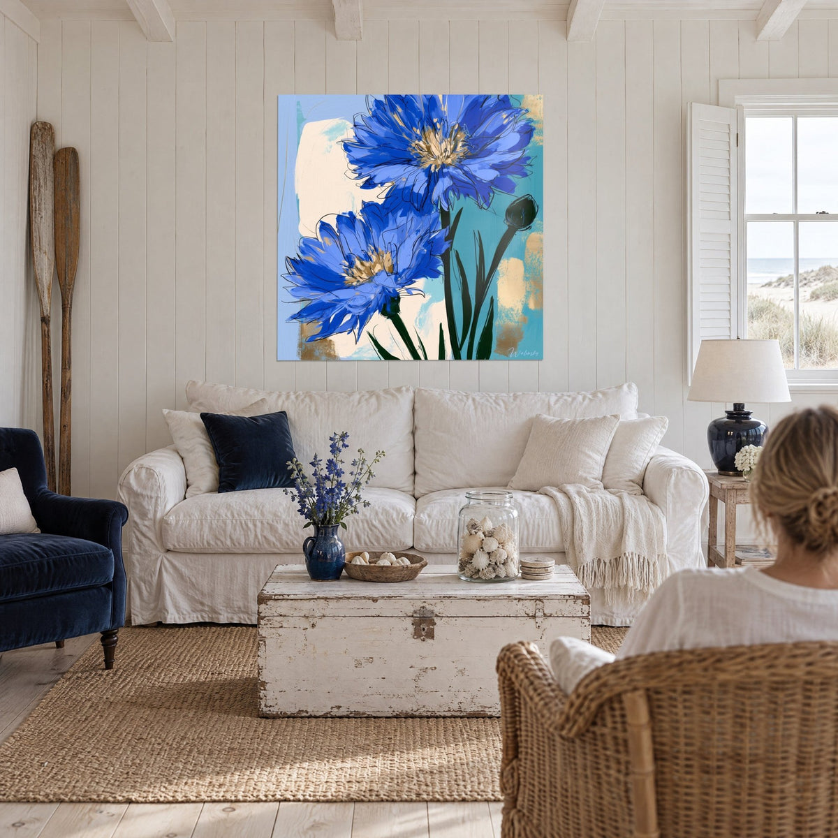 Tableau bleuets bleu roi aux cœurs dorés sur fond turquoise et crème, au-dessus d'un canapé dans un salon lumineux