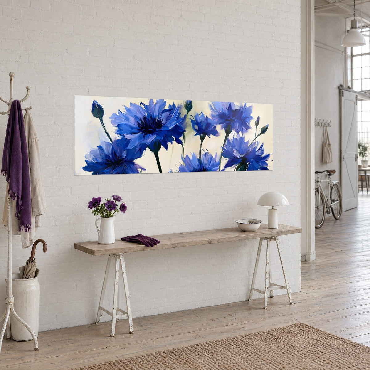 Tableau gerbe de centaurées indigo sur fond crème, tiges vertes élancées, accroché au-dessus d'une console en bois clair