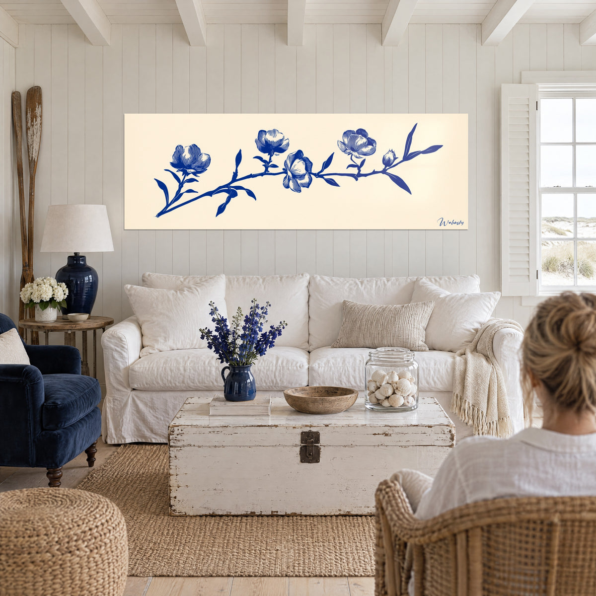 Schilderij van een bloeiende tak in marineblauwe gravure op ivoorkleurige achtergrond, vijf open bloemen, boven een bank in een lichte woonkamer