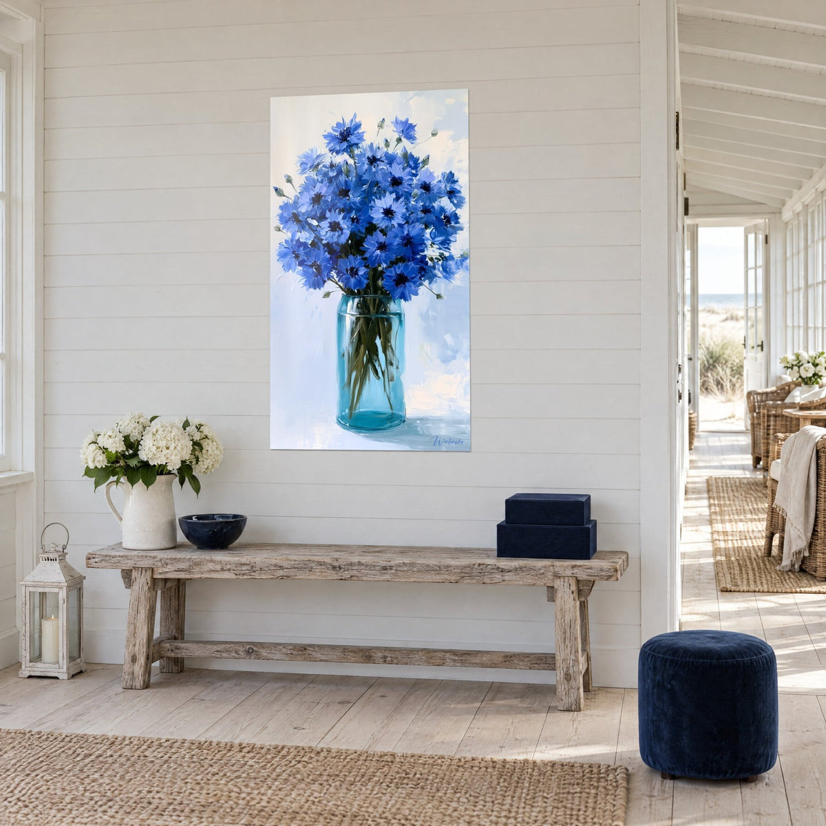 Tableau gerbe de fleurs bleu outremer dans un vase transparent aux tiges vertes, sur mur lambrissé blanc, maison de bord de mer