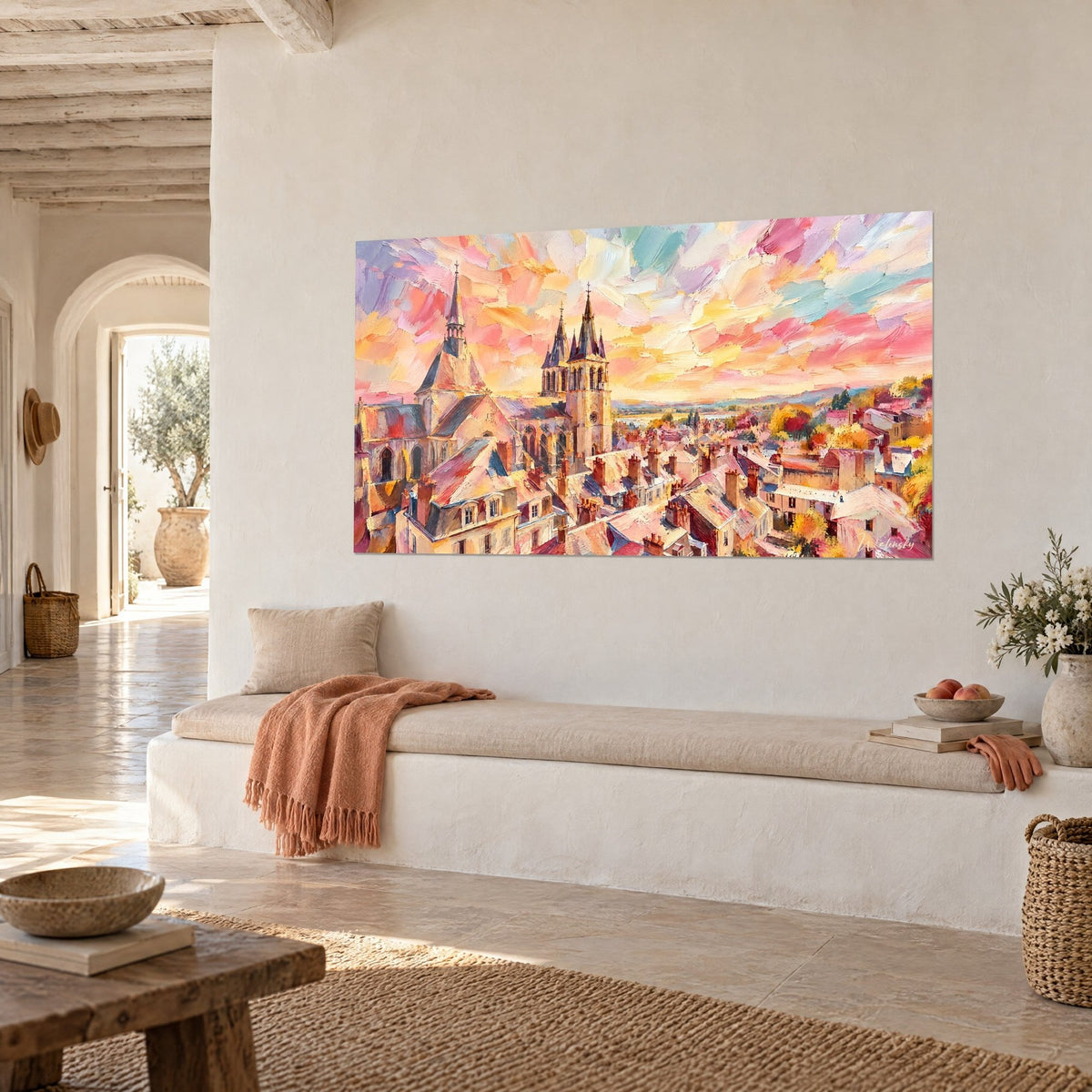 Quadro di campanili appuntiti e tetti di tegole rosate sotto nuvole arancioni e turchesi, panca bianca e plaid corallo