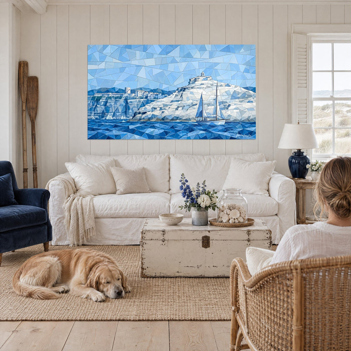 Cuadro velero blanco que bordea los acantilados de Bonifacio en facetas azules, golden retriever tumbado sobre un sofá en un salón luminoso