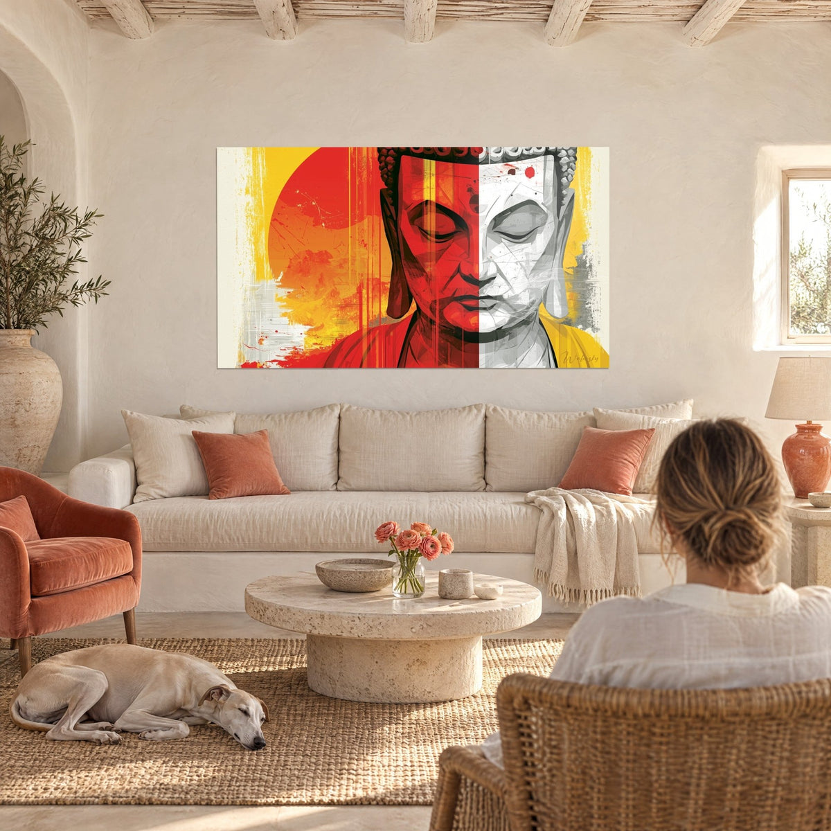 Tableau visage de Bouddha moitié rouge, moitié gris, soleil orangé, deux personnes de dos au-dessus d'un canapé dans un salon lumineux