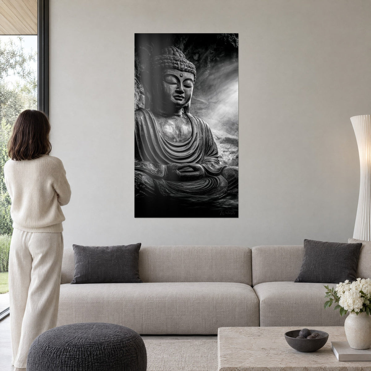 Tableau bouddha de pierre aux paupières closes, gris charbon et blanc brumeux, au-dessus d'un canapé dans un salon lumineux