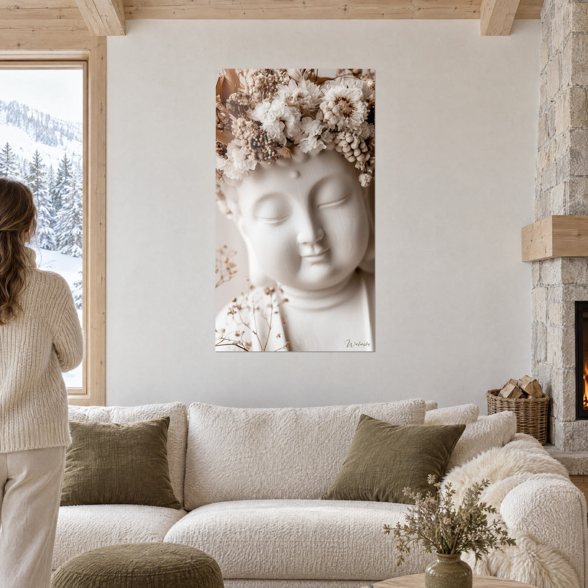 Tableau visage de Bouddha en plâtre blanc, couronne de fleurs séchées beige, au-dessus d'un canapé dans un salon lumineux