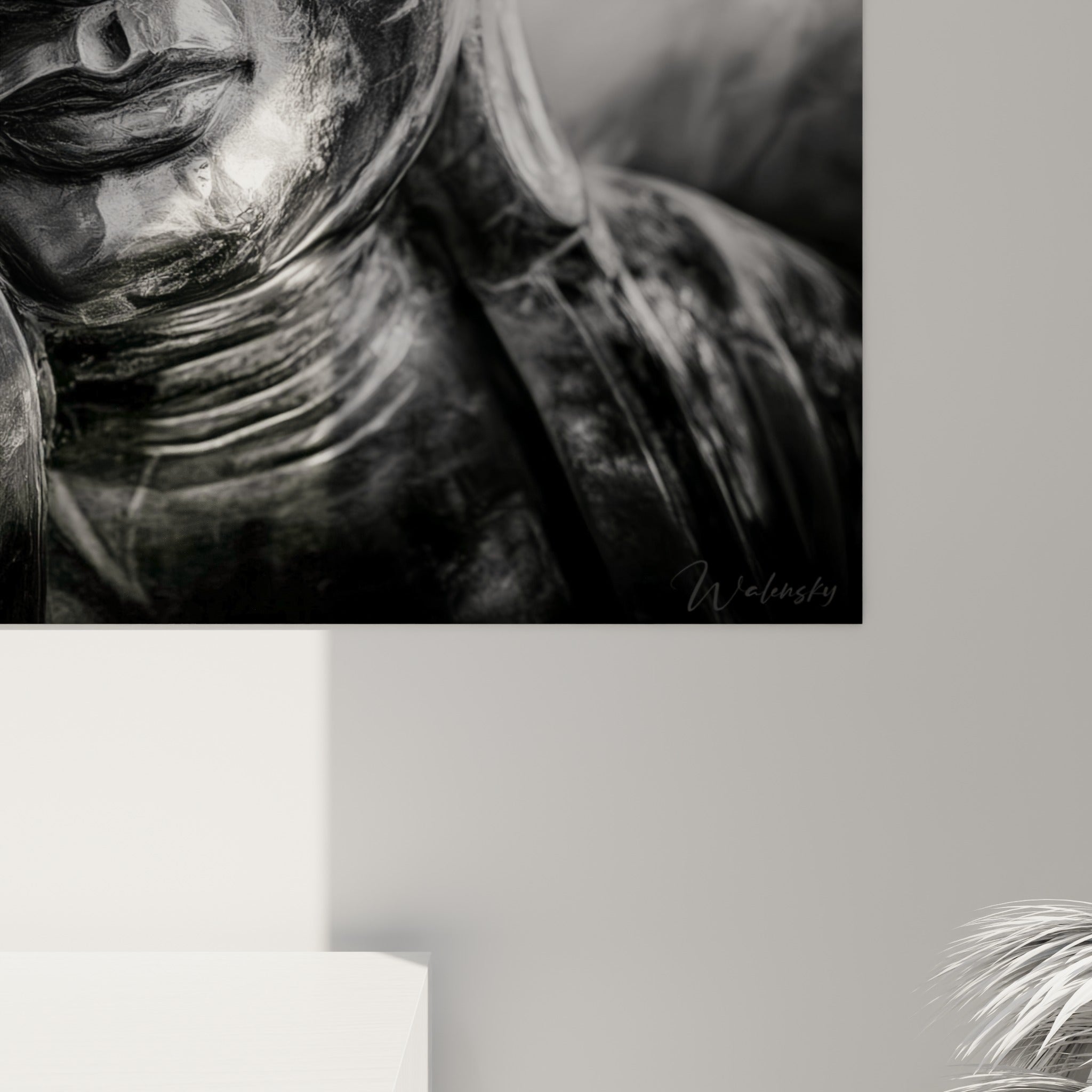 Grain photographique visible sur le visage sculpté du Bouddha, contrastes noirs et reflets argentés accrochés au mur