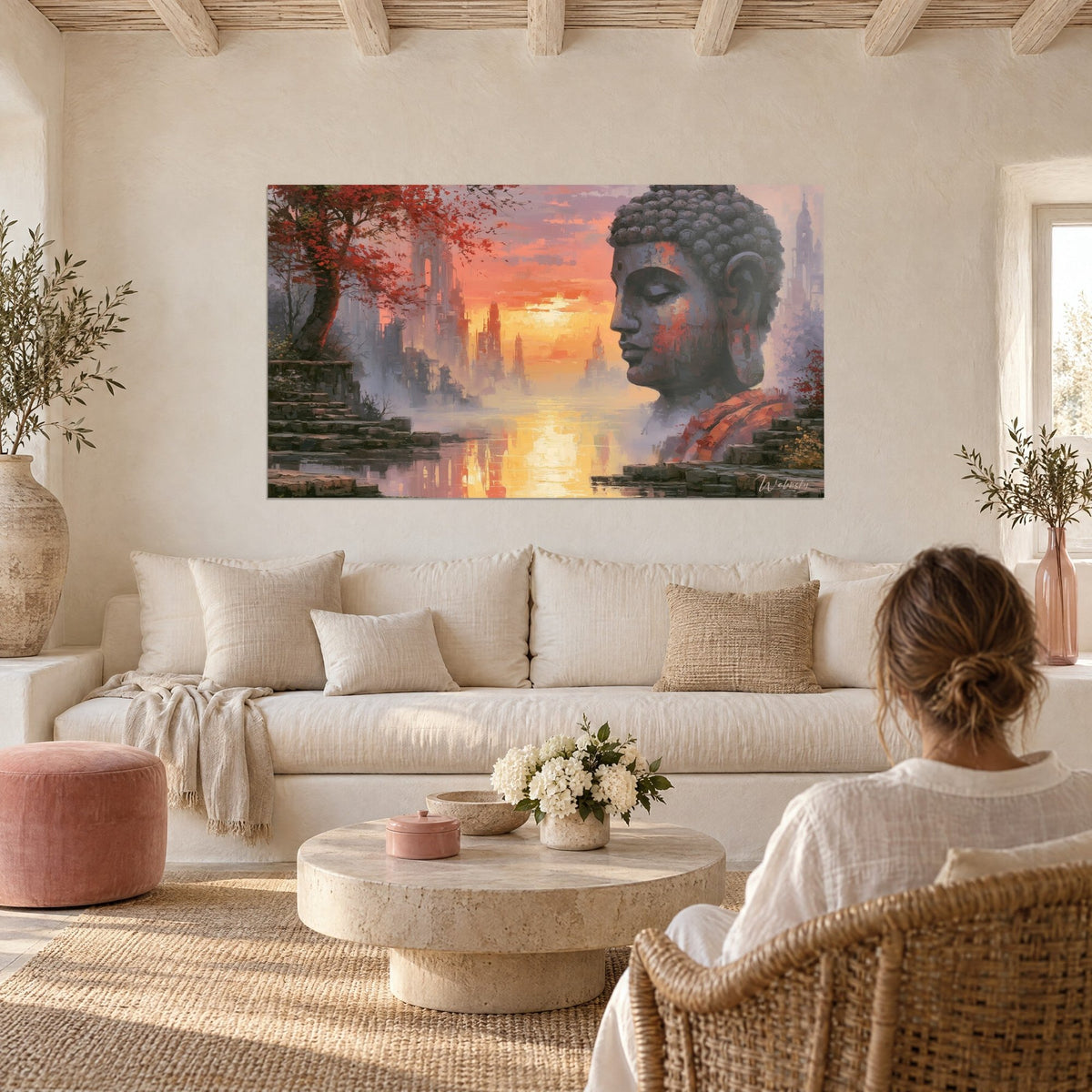 Tableau Bouddha de pierre grise en profil, ciel orange et rose sur lac brumeux, personne de dos, au-dessus d'un canapé dans un salon lumineux