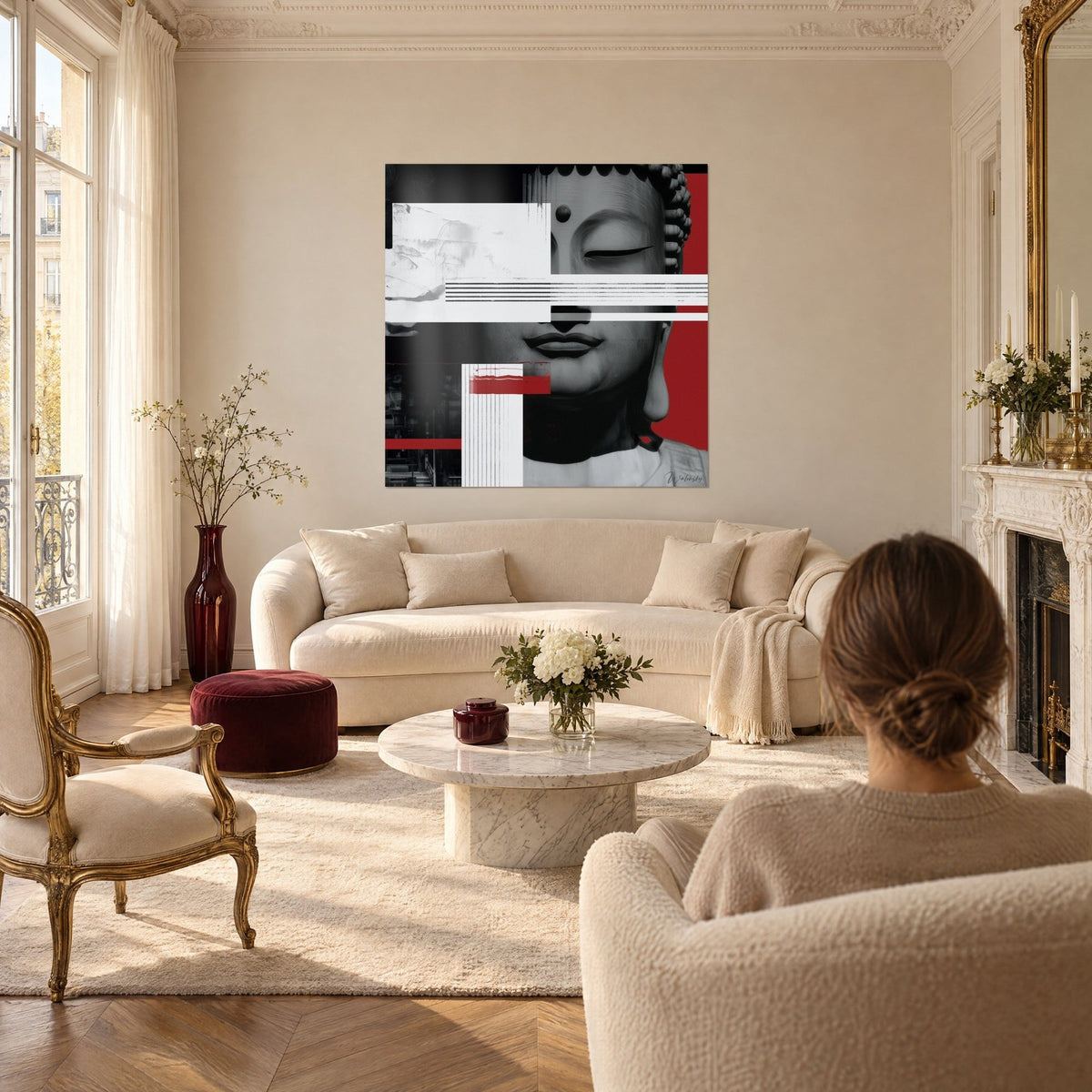 Tableau visage de Bouddha gris et rouge aux bandes blanches superposées, femme de dos, au-dessus d'un canapé dans un salon lumineux