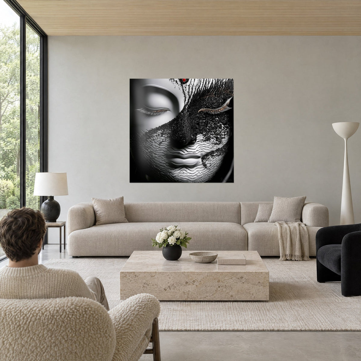 Tableau visage de Bouddha mi-porcelaine blanche, mi-croûte noire, paupière dorée close, au-dessus d'un canapé dans un salon lumineux