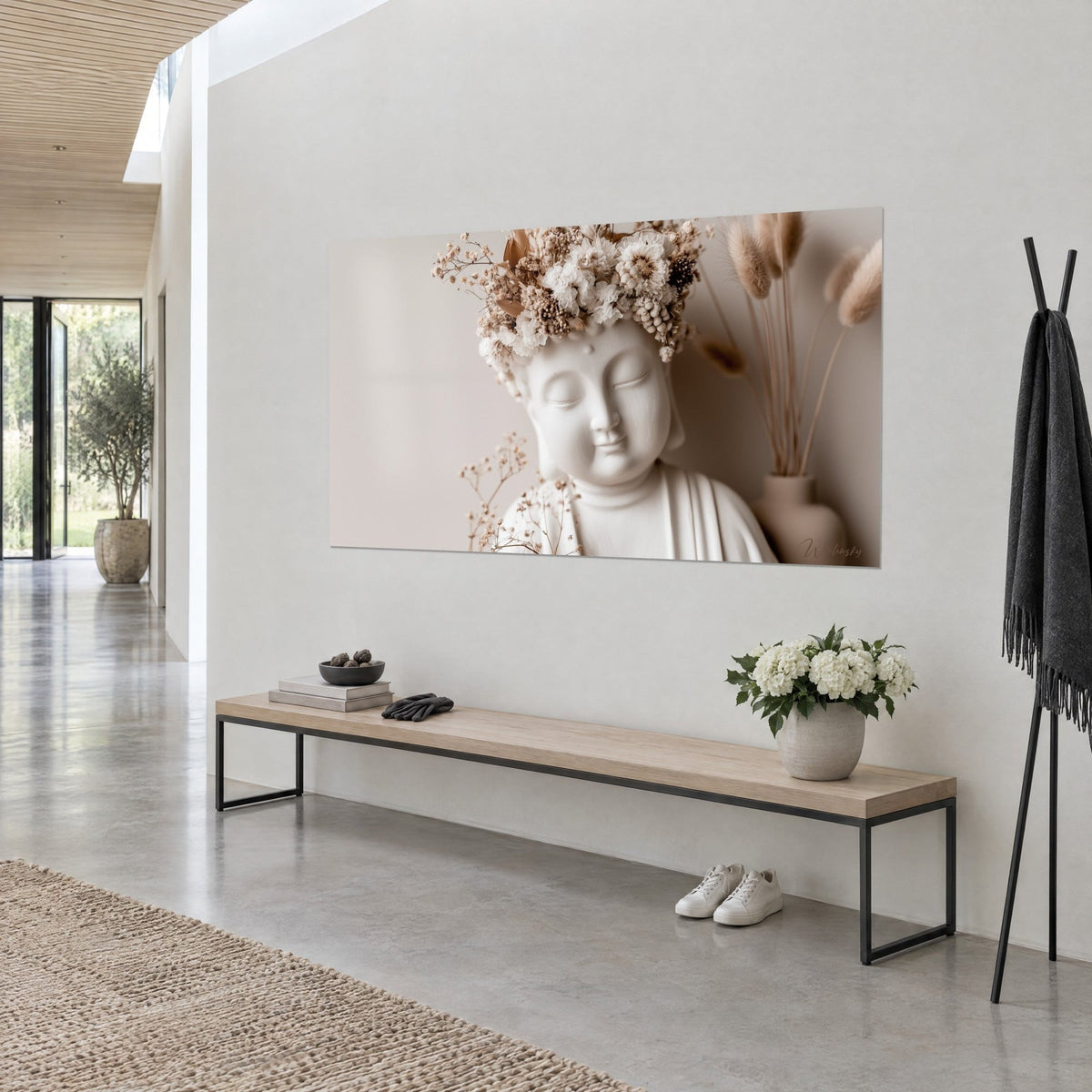 Tableau Bouddha de plâtre crème coiffé de gypsophile et chrysanthèmes blancs, pampas dorés, sur mur gris clair d'un couloir ouvert