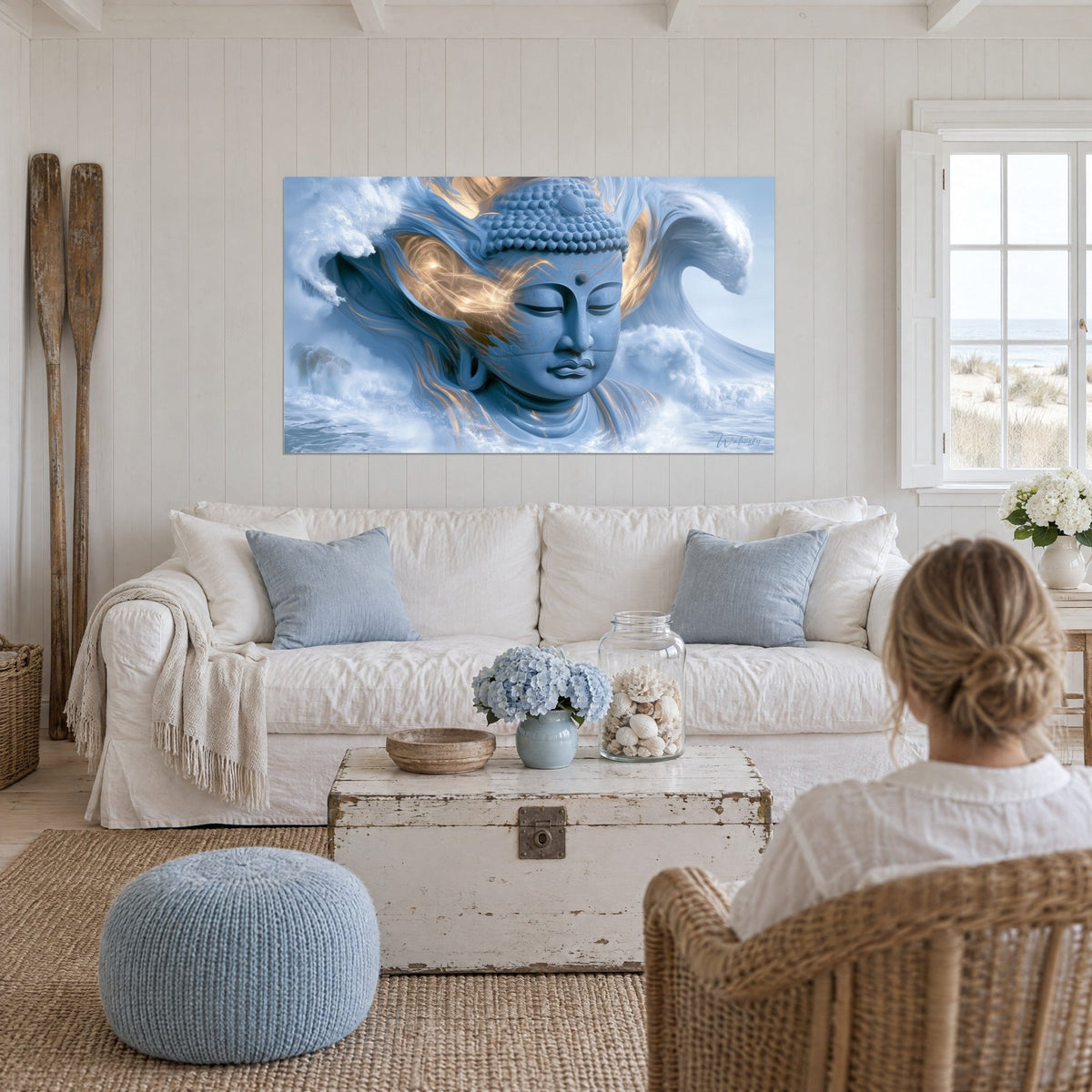 Tableau visage de Bouddha bleu ciel auréolé d'or, vague blanche en crête, au-dessus d'un canapé dans un salon lumineux