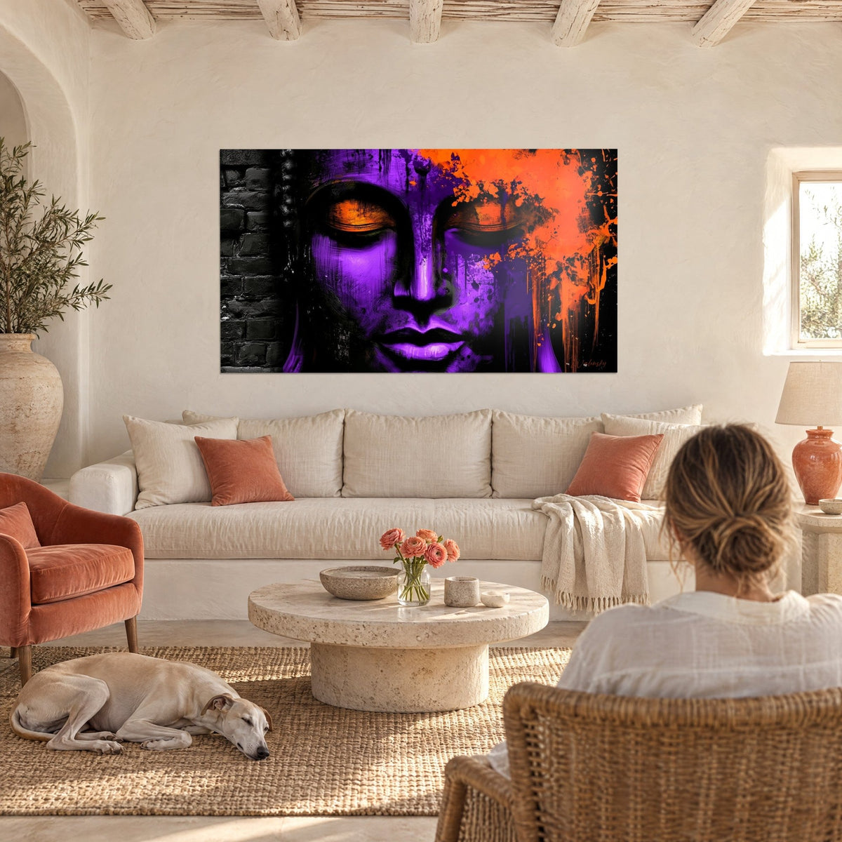 Schilderij paars Boeddhagezicht met oranje oogleden en inktspatten, boven een bank in een lichte woonkamer