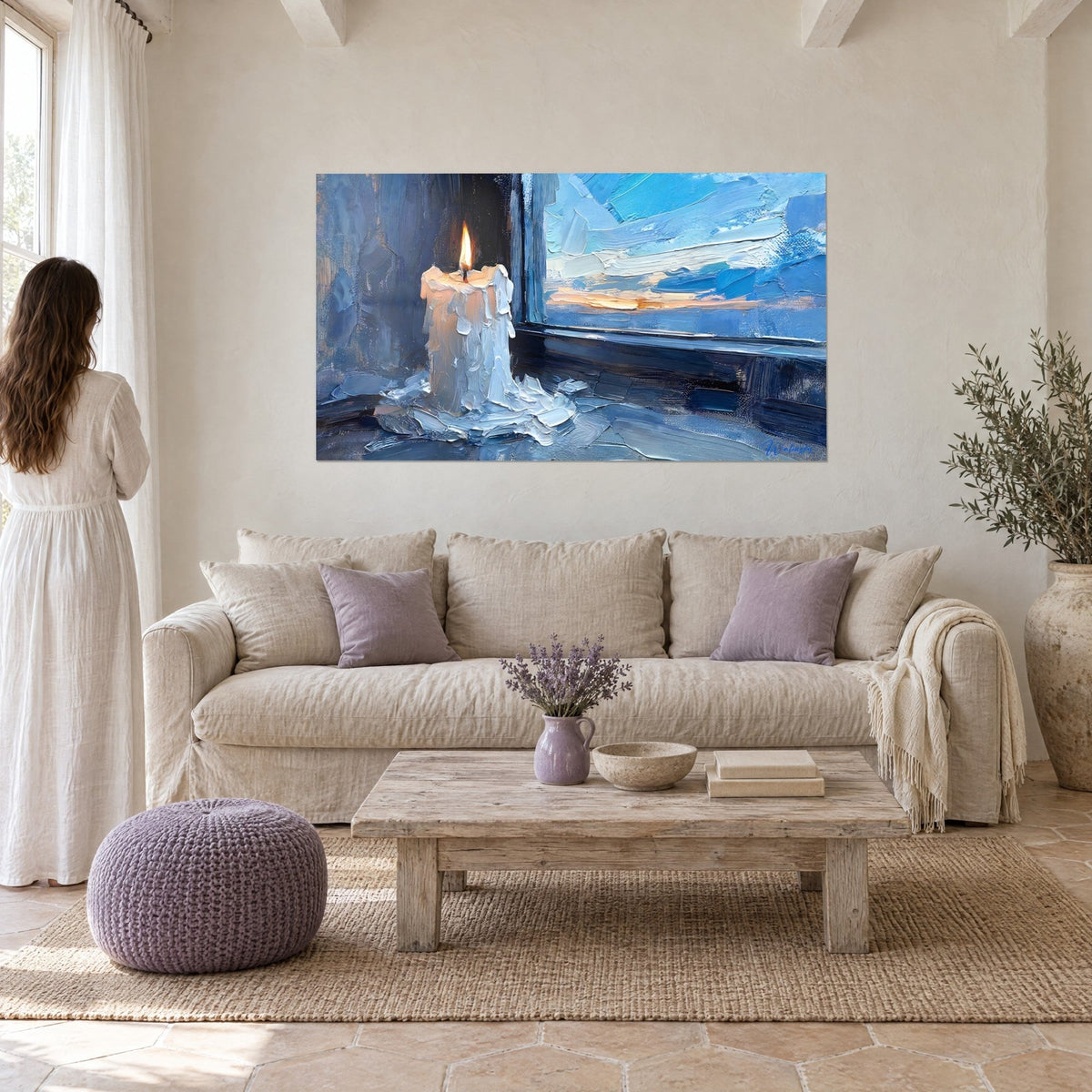 Cuadro de una vela blanca con goterones de cera congelados, cielo azul y naranja en la ventana, encima de un sofá en un salón luminoso