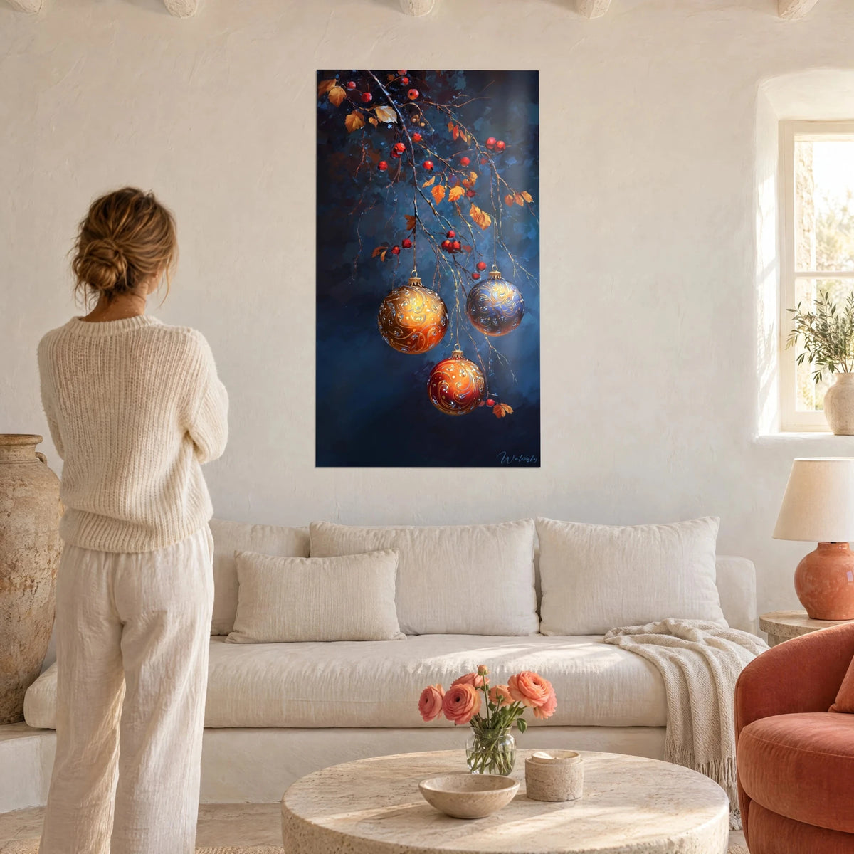 Schilderij met koperkleurige kerstballen aan een tak, middernachtblauw en oranje, vrouw van achteren boven een bank in een lichte woonkamer