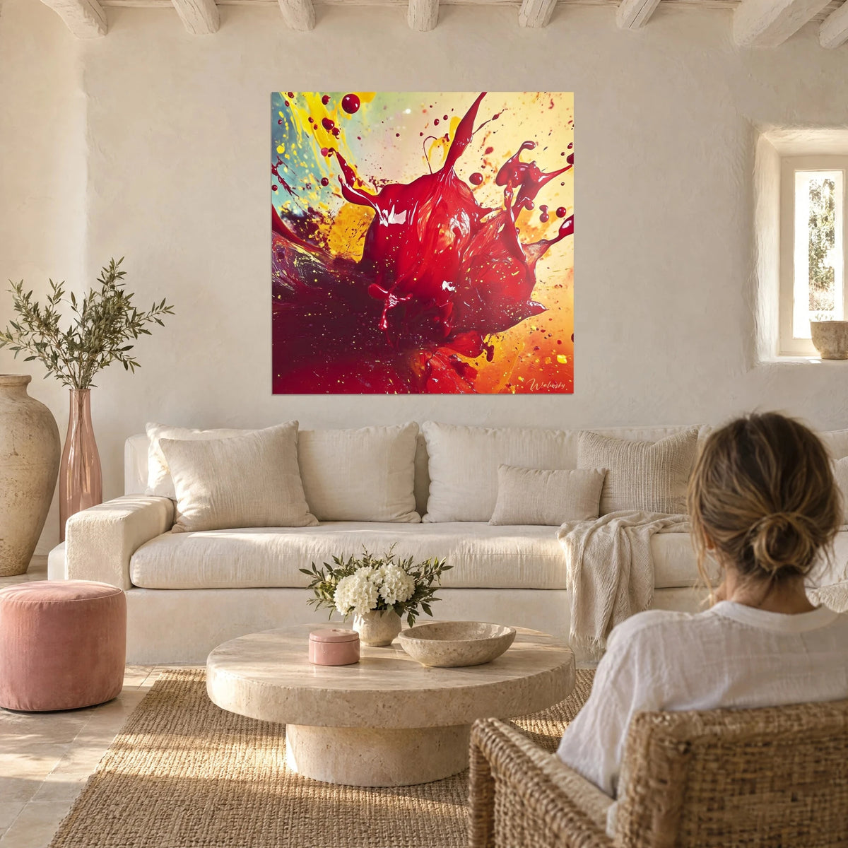 Tableau éclaboussure de peinture rouge carmin sur fond jaune safran, femme de dos, au-dessus d'un canapé dans un salon lumineux