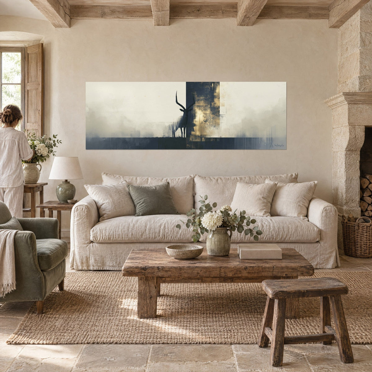 Tableau antilope aux cornes torsadées en ombre noire sur fond crème et or patiné, au-dessus d'un canapé dans un salon lumineux