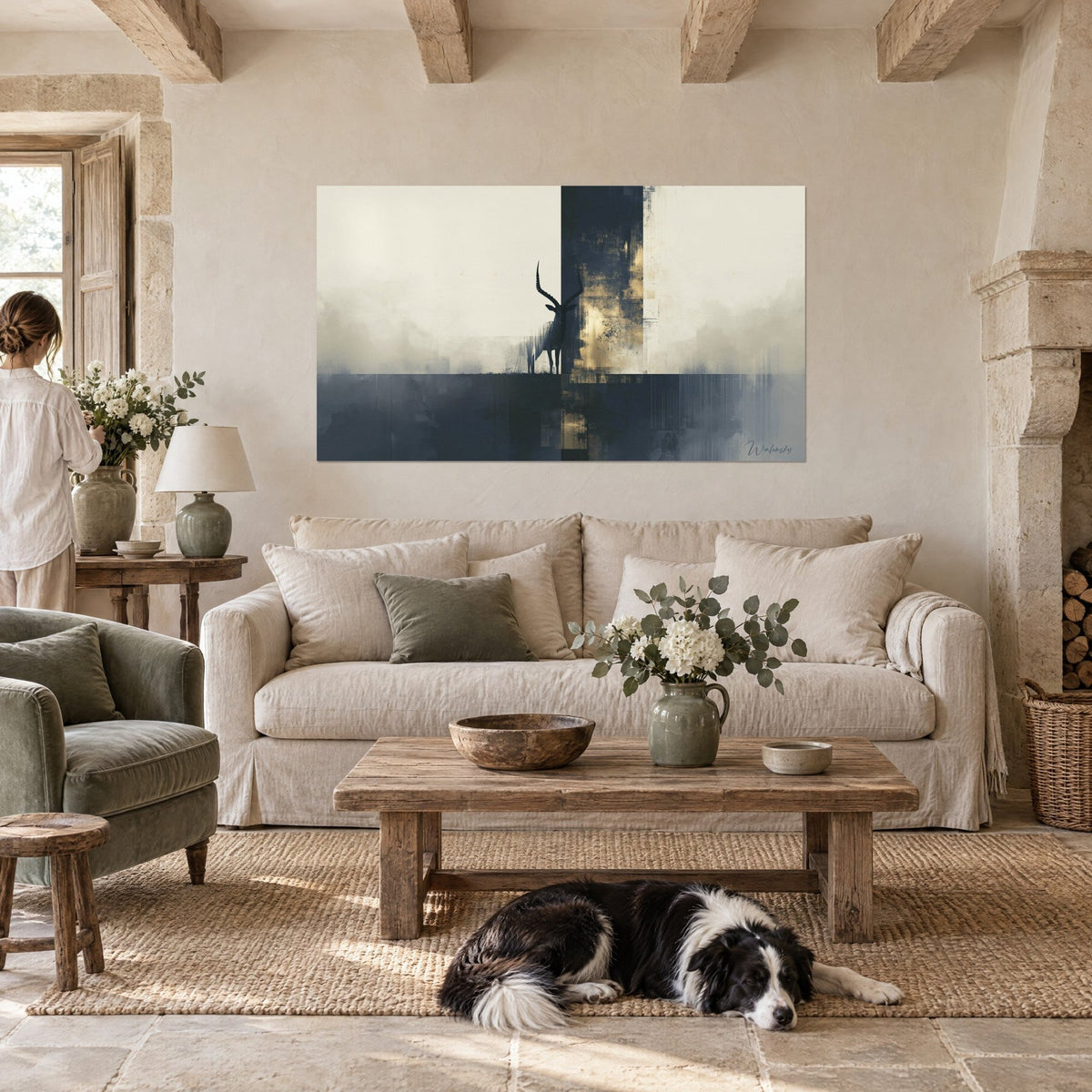 Wall art ibex with long horns in a navy blue silhouette on ivory mist and gold flecks, hanging above a sofa in a bright living room