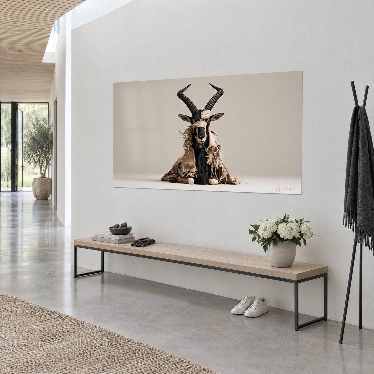 Wall art dark seated antelope with arched lyre horns and frayed raw canvas sack fabric, hanging in a light grey concrete hallway