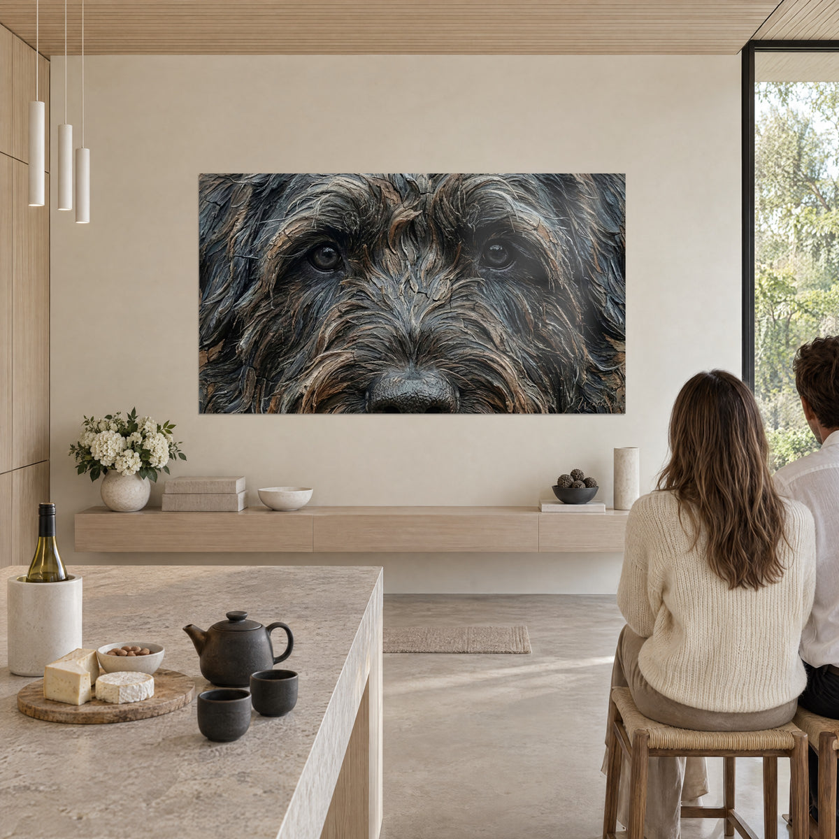 Gemälde eines Hundekopfes mit buschigen grauen und braunen Augenbrauen, bernsteinfarbenen Augen, hängend in einer offenen Küche, zwei Personen von hinten am Tisch