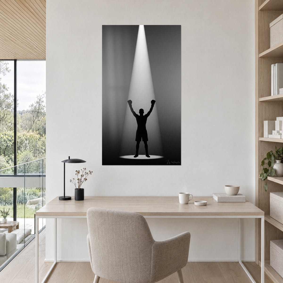 Quadro sagoma nera di pugile sotto un faretto bianco, sfondo grigio profondo, appeso sopra una scrivania in legno chiaro