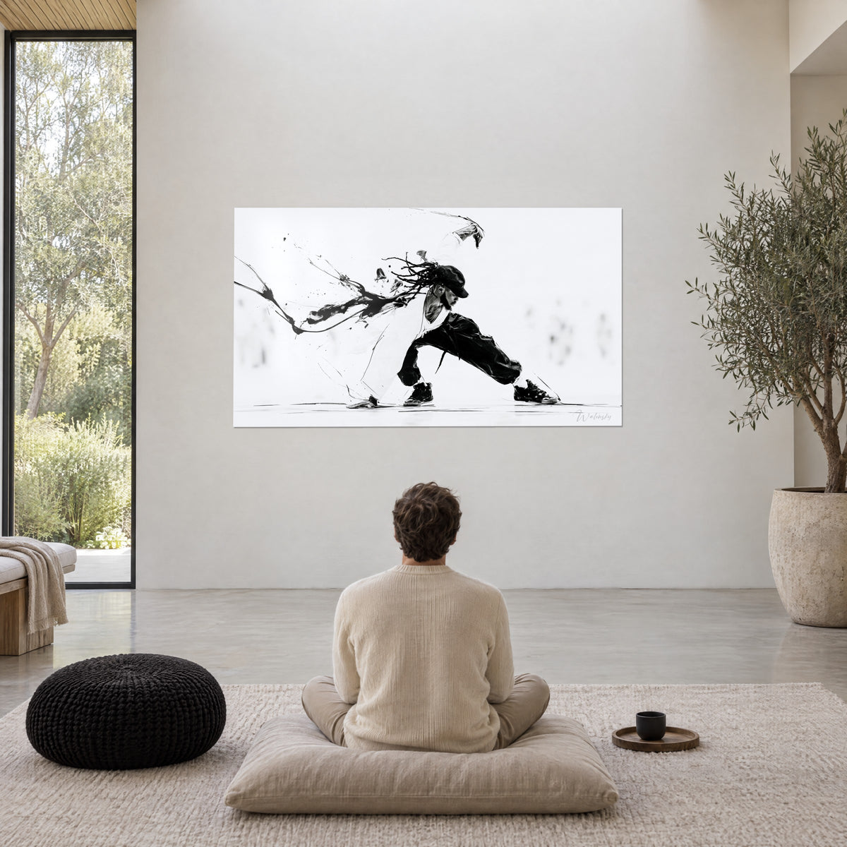 Wall art of a frozen movement of a hip-hop dancer with ink strands, deep black on white, viewed from behind by a man seated on a cushion in front of an olive tree