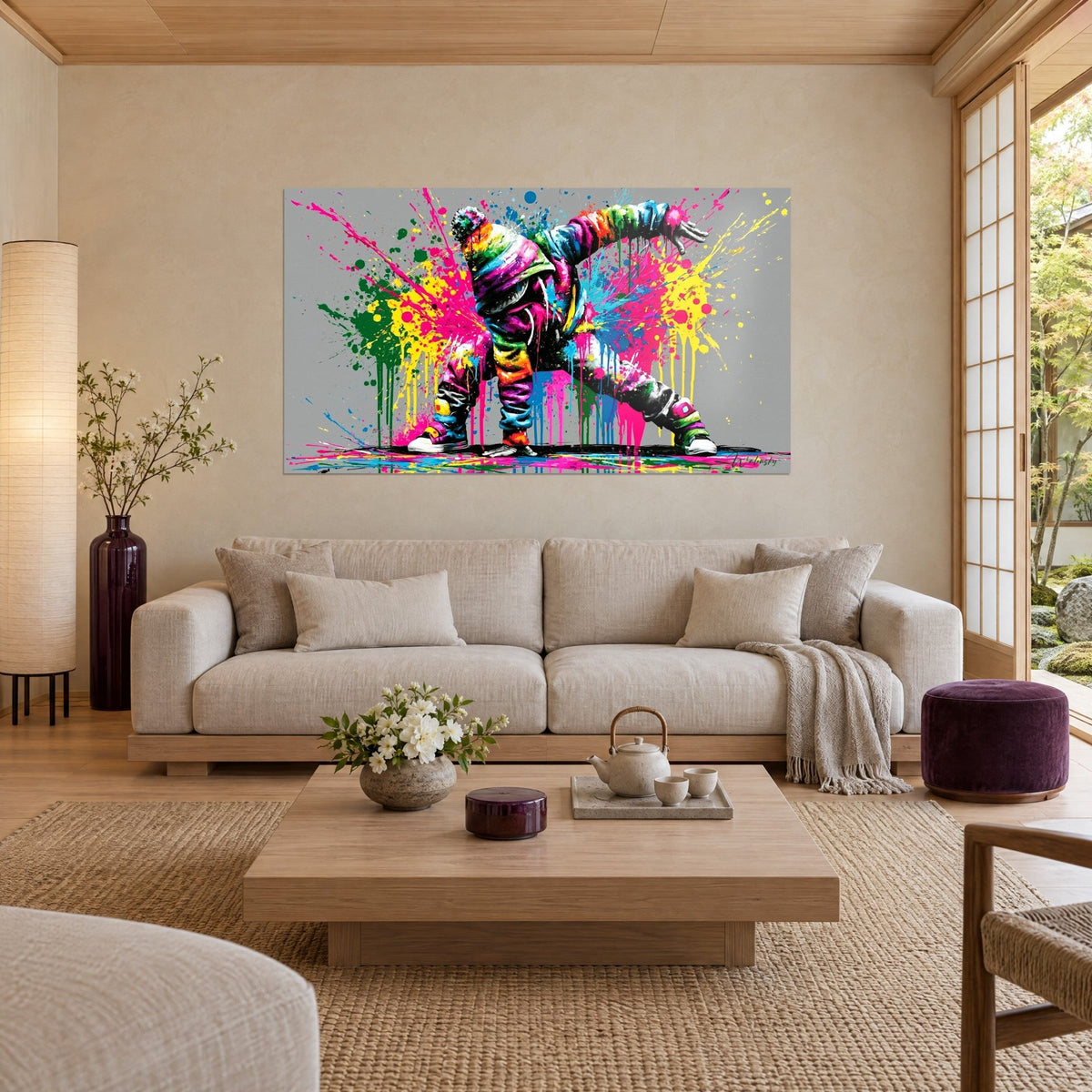 Wall art of a breakdancer in pink and yellow splashes on a grey background, above a sofa in a bright living room