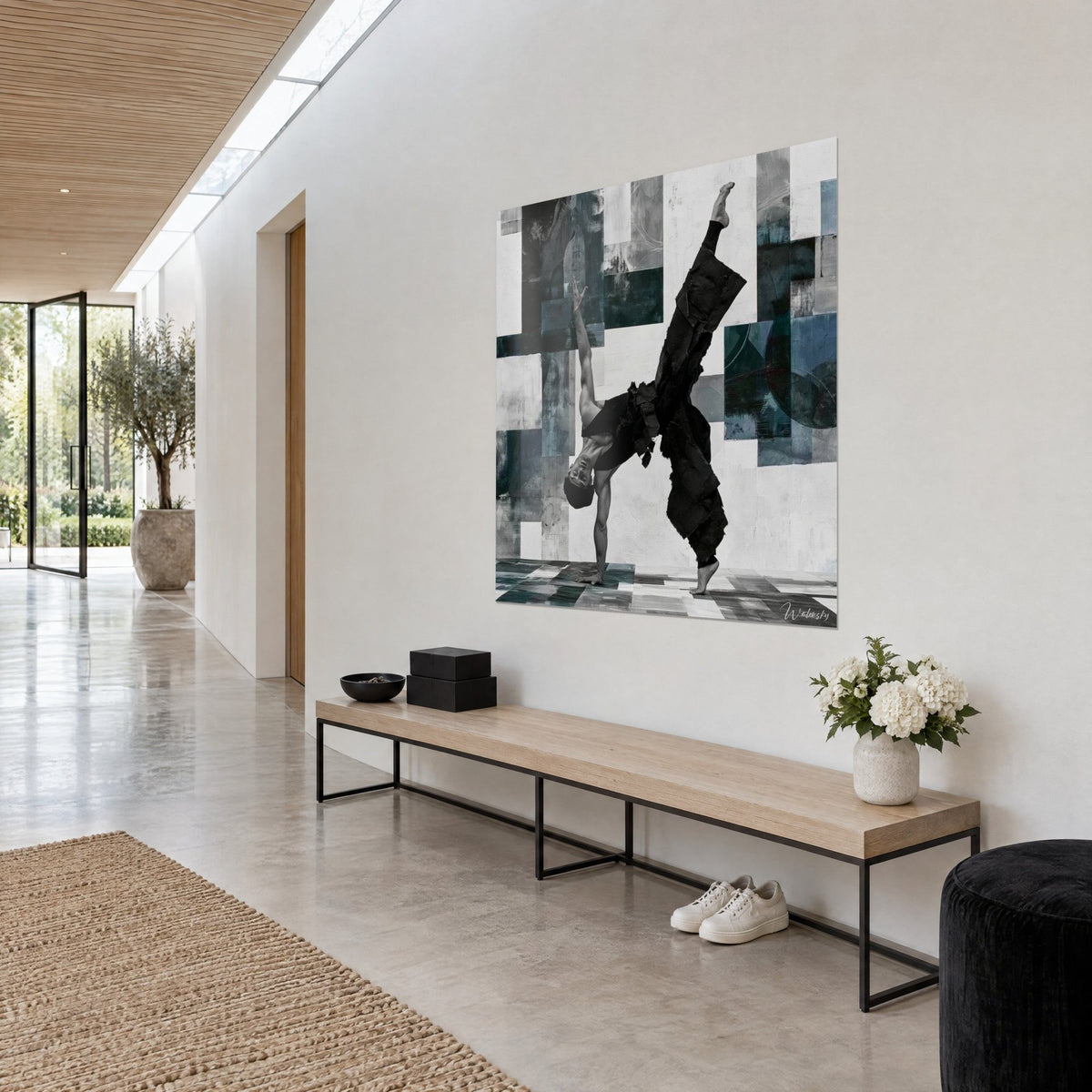 Cuadro b-boy con la pierna estirada hacia el cielo, ropa negra texturizada sobre pared de cuadros gris y verde oscuro, vista de tres cuartos en un pasillo claro