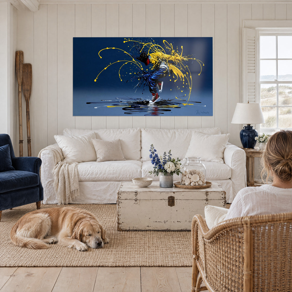 Tableau danseur de breakdance éclaboussé de jaune et bleu marine, baskets rouges, au-dessus d'un canapé dans un salon lumineux