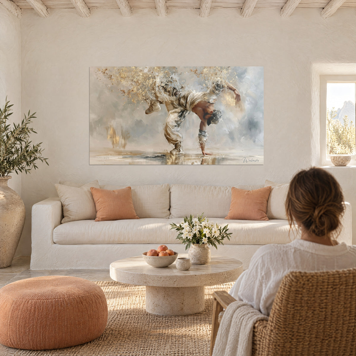 Tableau breakdanseur en appui sur une main, pantalon crème et éclats d'or soufflés, fond gris bleuté, au-dessus d'un canapé dans un salon lumineux