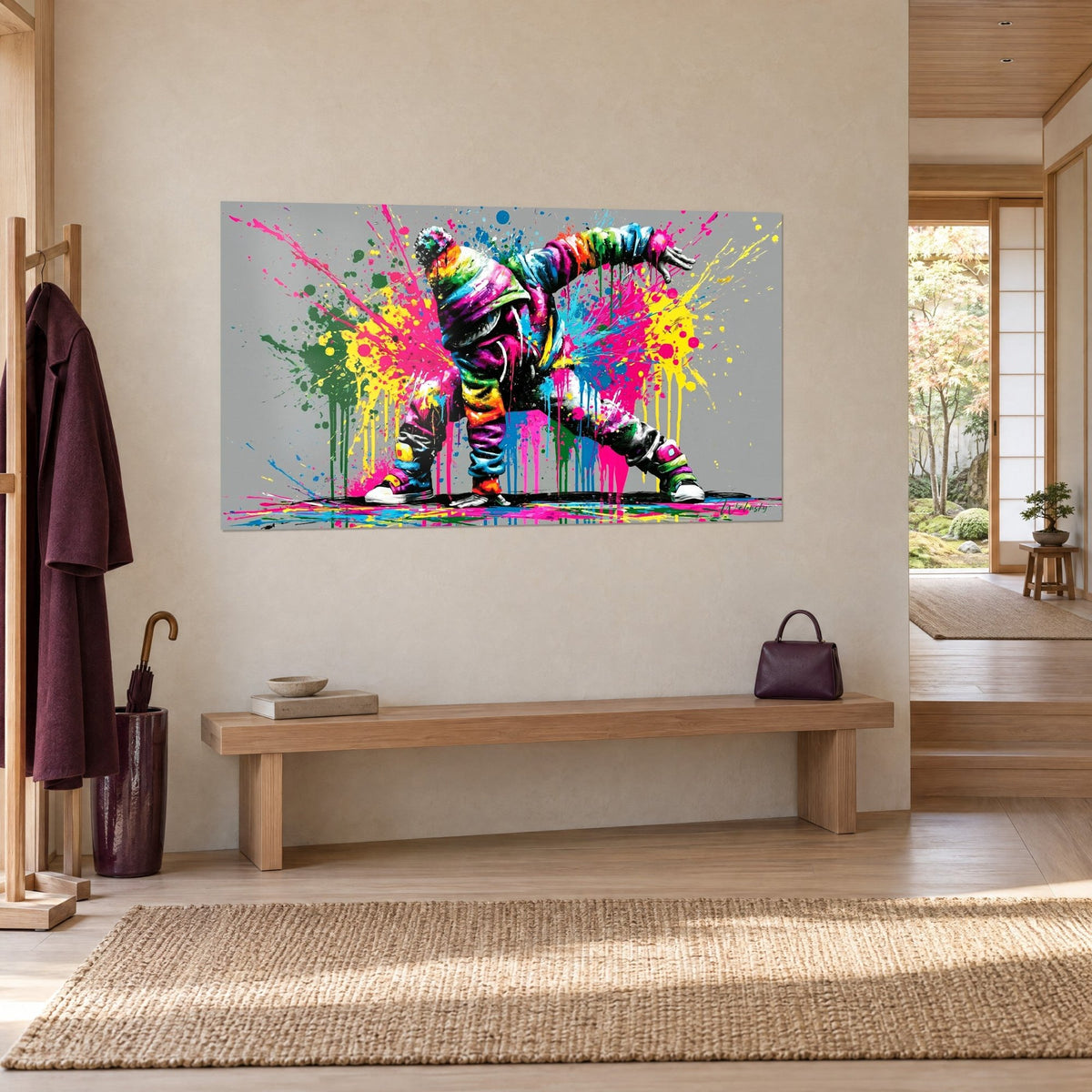 Wall art of a b-boy in a rainbow hoodie, legs spread in a burst of fuchsia and yellow, on a beige wall beside a bench