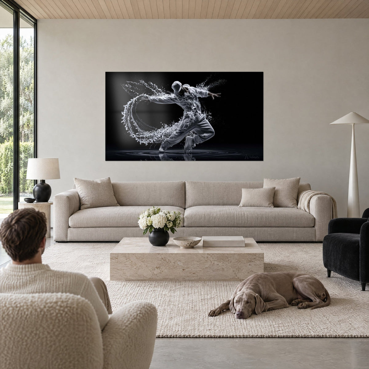 Tableau breakdanseur en sweat gris clair, bras écartés dans un arc d'eau blanche sur fond noir, au-dessus d'un canapé dans un salon lumineux