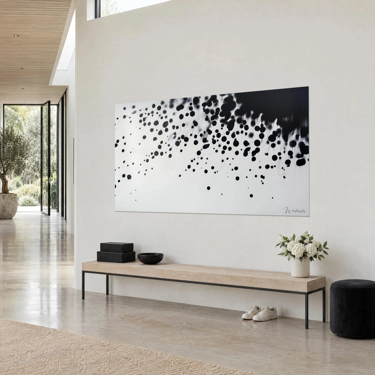 Wall art with cloud-like ink splashes on cream white background, dark mass at upper right, three-quarter view, light wood bench