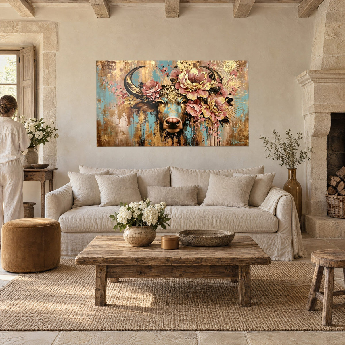 Tableau buffle aux cornes sombres couronné de pivoines roses, fond turquoise et or, au-dessus d'un canapé dans un salon lumineux