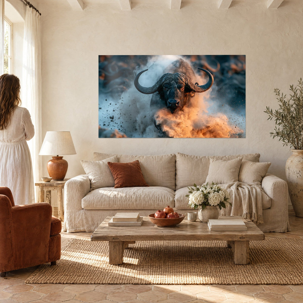 Quadro bufalo cornuto che emerge da una nuvola ocra, muso nero e polvere arancione, sopra un divano in un soggiorno luminoso