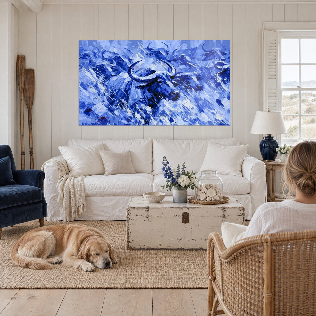 Cuadro búfalo azul cobalto con cuernos en forma de media luna, trazos blancos con espátula, sobre un sofá en un salón luminoso
