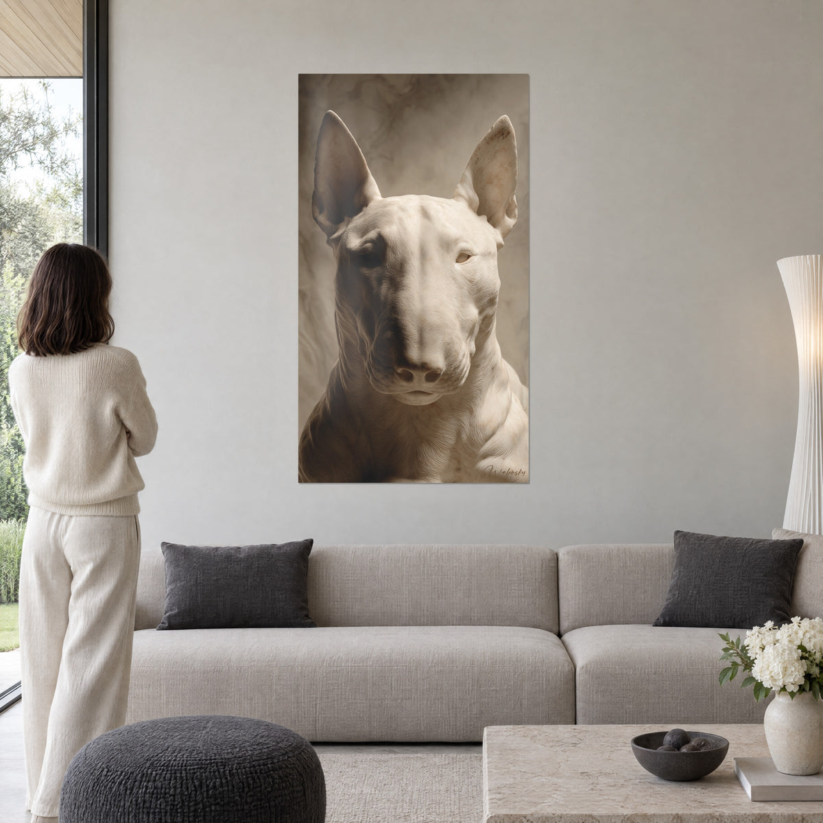 Obraz biały bull terrier rzeźbiony na wzór marmuru, uniesione uszy, sepiowe tło, kobieta tyłem, nad kanapą w jasnym salonie