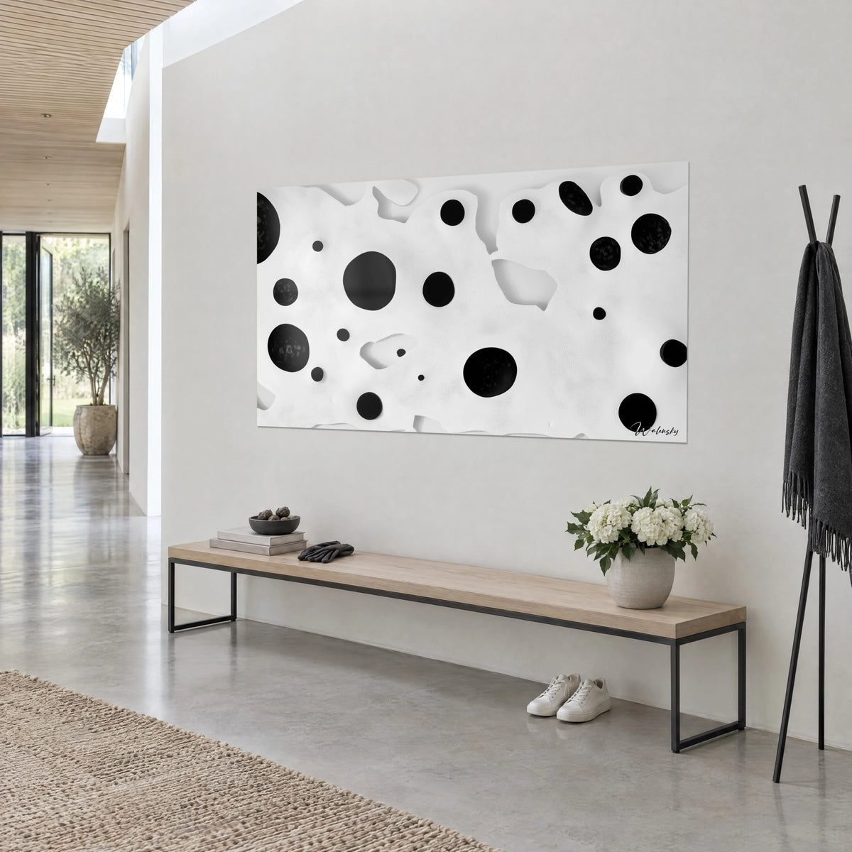 Wall art with scattered round ebony spots on a carved ivory background, three-quarter view, light wooden bench, white bouquet, airy entrance