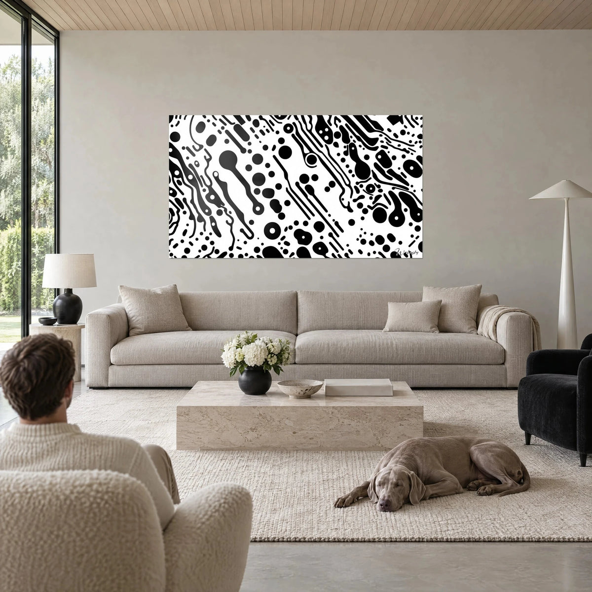 Schilderij met zwart-witte gestipte print van bellen en diagonale strepen, twee personen van achteren, Weimaraner, boven een bank in een lichte woonkamer