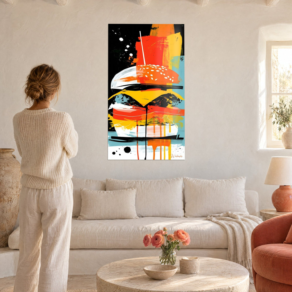Quadro hamburger impilato in pennellate arancioni e gialle su fondo nero, una donna di spalle, sopra un divano in un soggiorno luminoso
