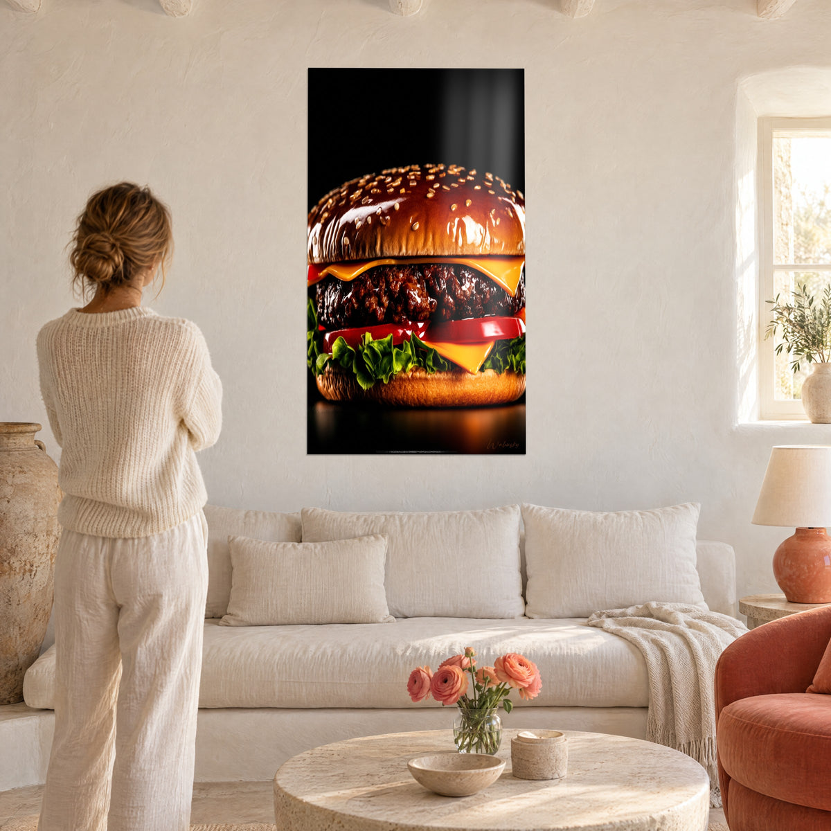 Quadro cheeseburger lucido, panino al sesamo dorato e pomodoro rosso, osservato da una donna di spalle sopra un divano in un soggiorno luminoso
