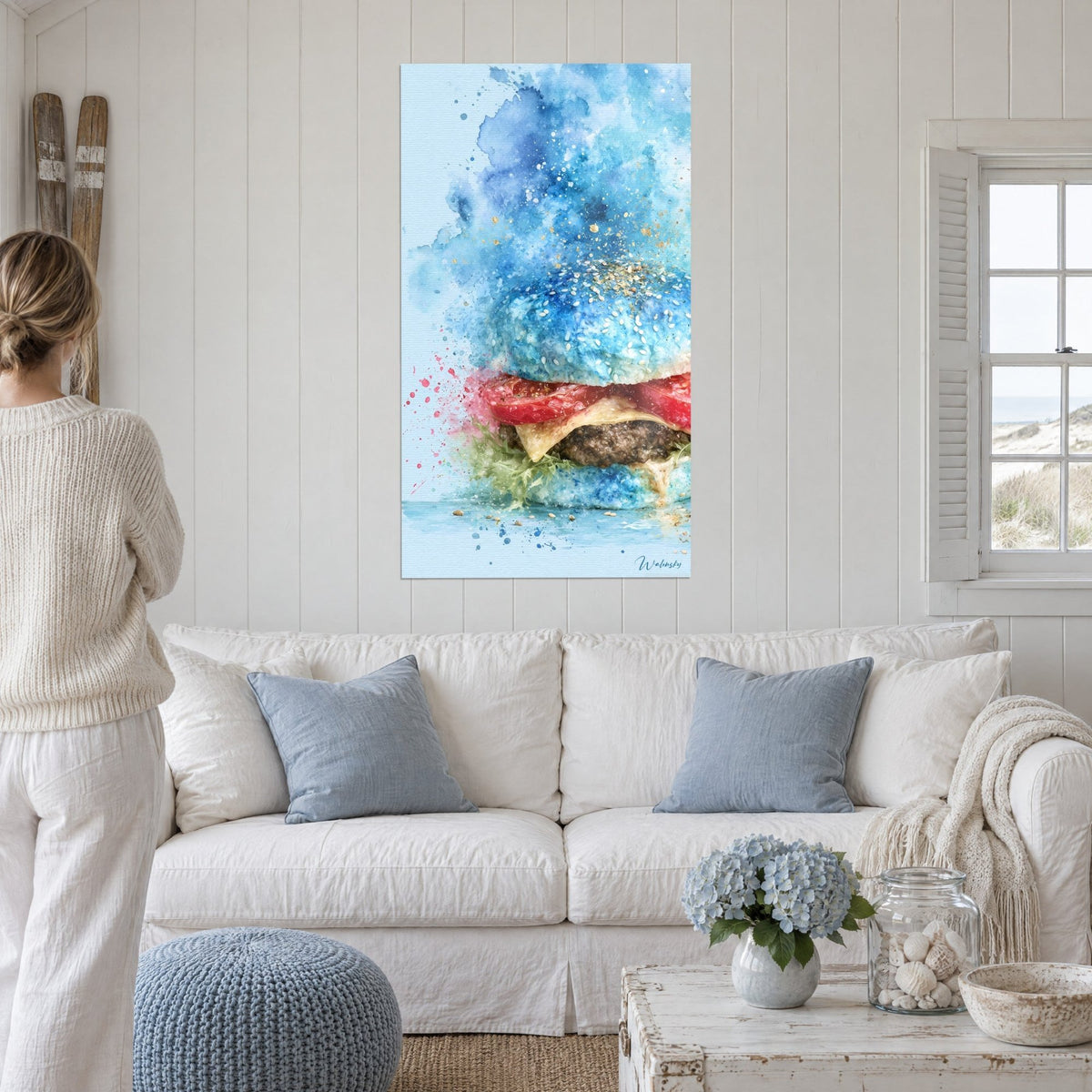Wall art azure blue sesame bun burger, bright red tomato, cream cheese, above a sofa in a bright living room