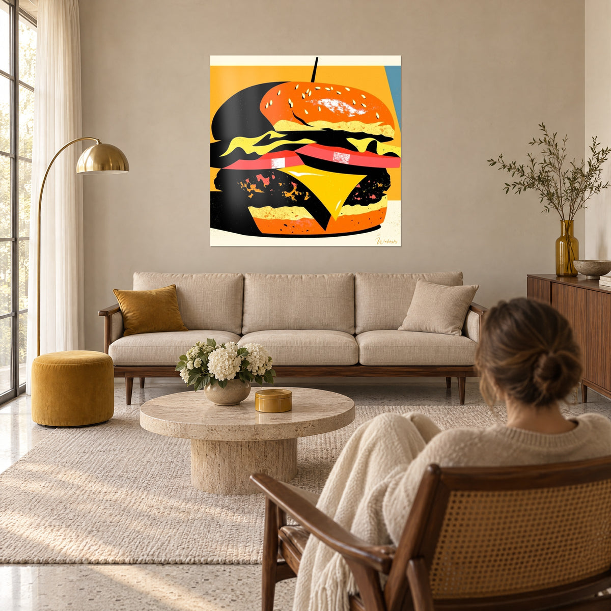 Tableau hamburger graphique noir et orange, graines de sésame dorées, fromage jaune vif, au-dessus d'un canapé dans un salon lumineux