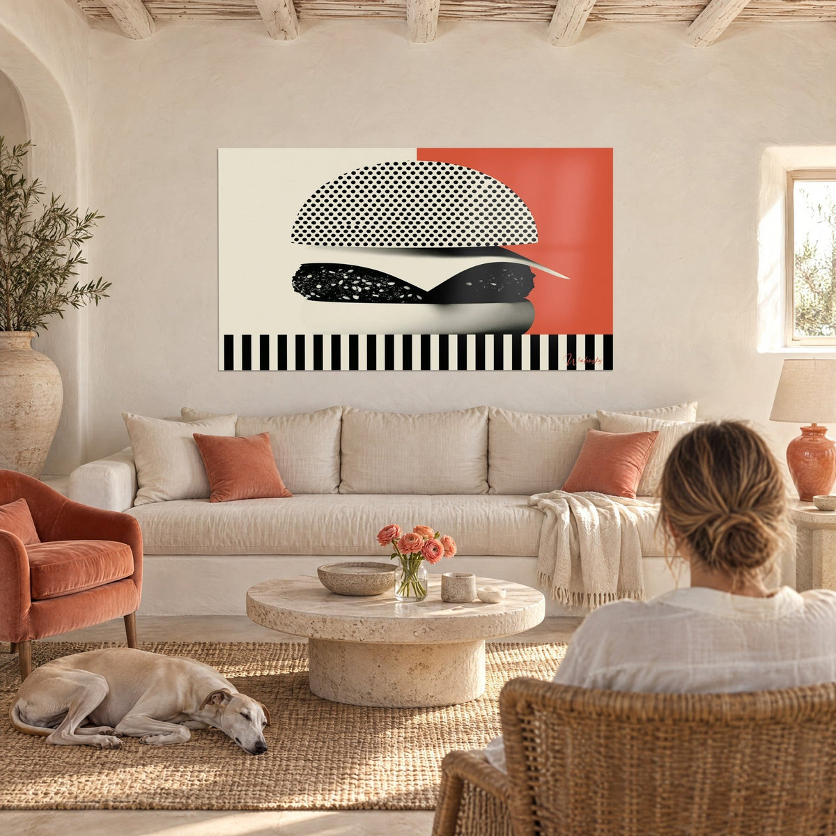 Πίνακας pop art μπέργκερ, μαύρες και κρεμ στιγμές σε ροζ κοραλί φόντο, δύο άνθρωποι από πίσω πάνω σε καναπέ σε φωτεινό σαλόνι