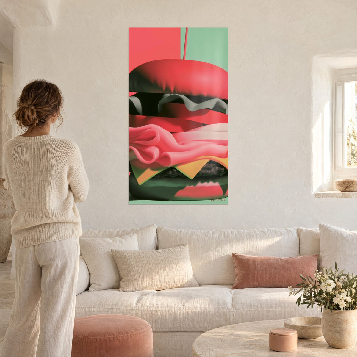 Wall art giant burger with coral red bun and wavy pink ham, a woman seen from behind above a sofa in a bright living room