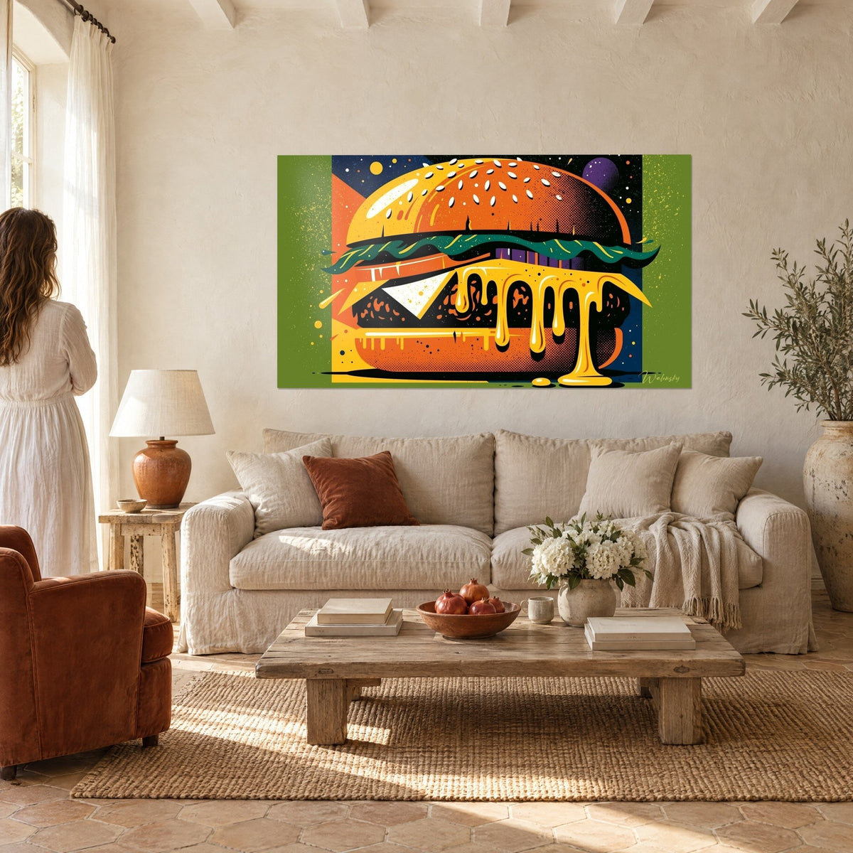 Quadro cheeseburger pop art con formaggio giallo che cola, panino arancione, sfondo verde, una donna di spalle, sopra un divano in un soggiorno luminoso