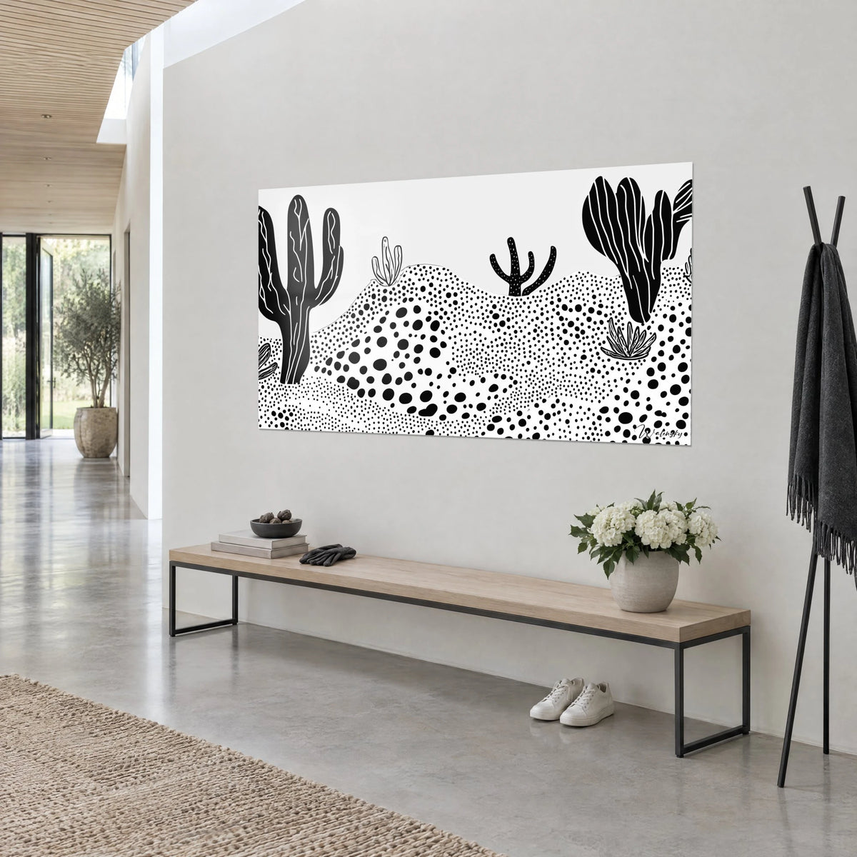Wall art of a black-and-white dotted desert, three cacti with light ribs, seen at an angle above a light wooden bench